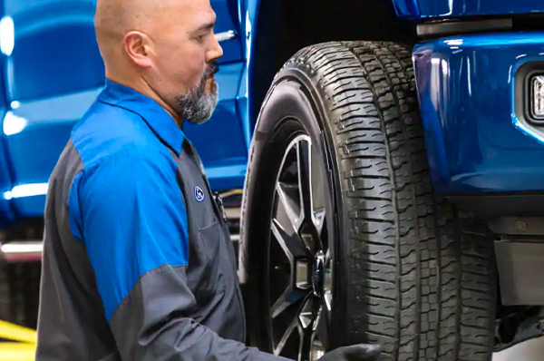 Bison Ford Service Offer - Low Price Tire Guarantee Ford Tech Putting On Tire On Vehicle