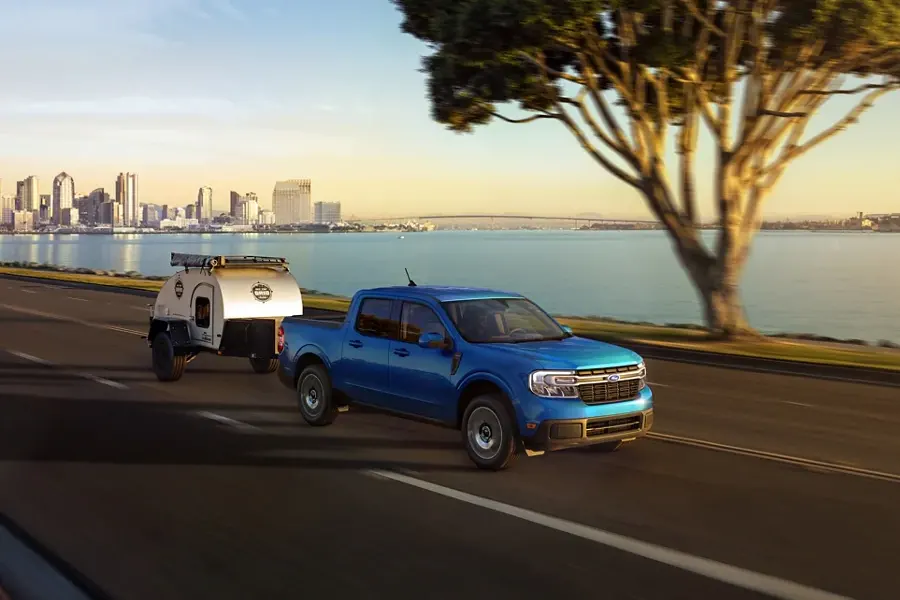 2022 Ford Maverick Performance - Available FX5 Off-Road Package Maverick towing a camper down highway driving away from a city