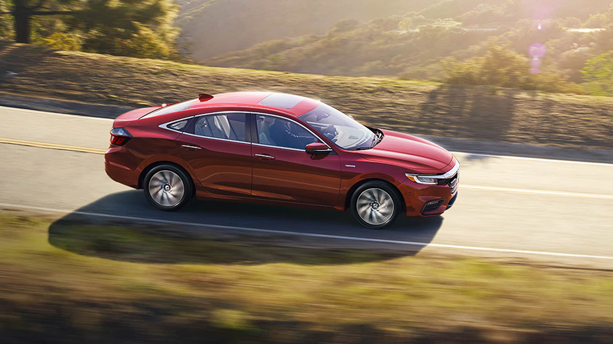 2021 Honda Insight Overhead passenger-side profile view of 2021 Honda Insight Touring in Radiant Red Metallic, driving on mountain road.