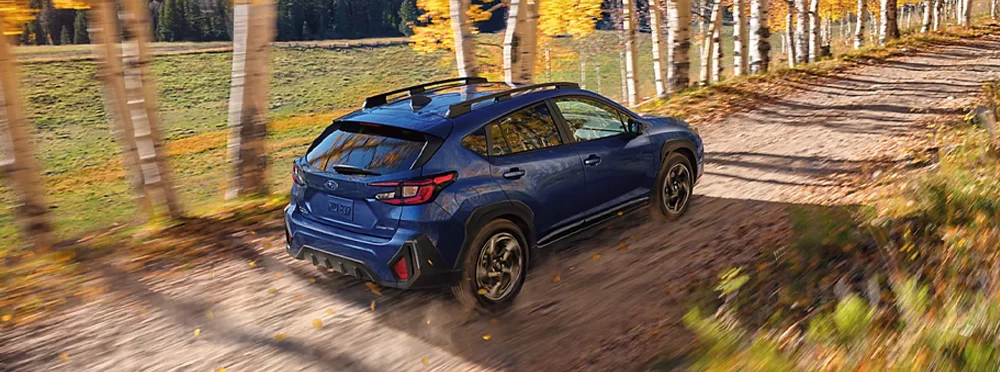 Crosstrek driving down woodland road